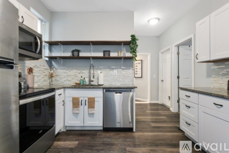 A kitchen with white cabinets and a marble backsplash.