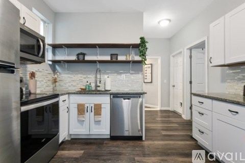 A kitchen with white cabinets and a marble backsplash.