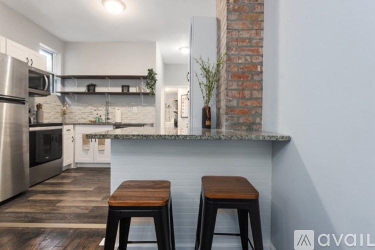 A kitchen with a white counter and a brick wall.