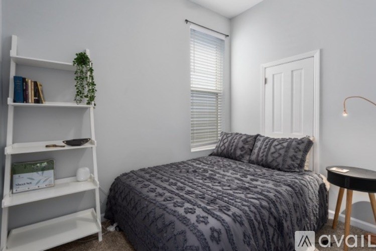 A bedroom with a bed, a bookshelf, and a small table.