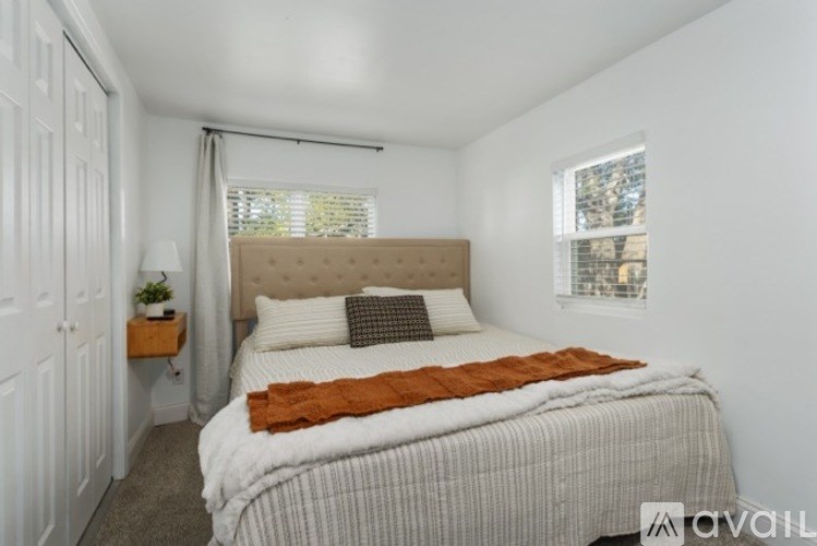 A bedroom with a bed, a window, and a small plant on a shelf.