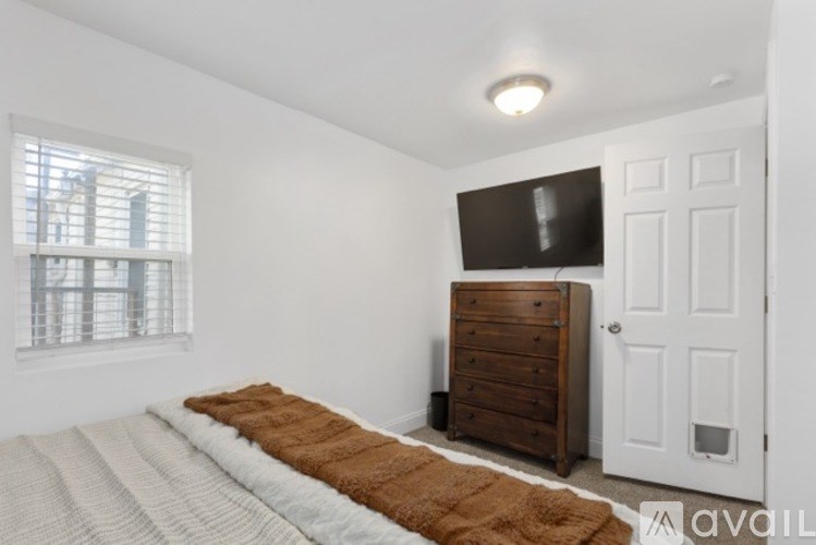 A bedroom with a bed, a dresser, and a window.