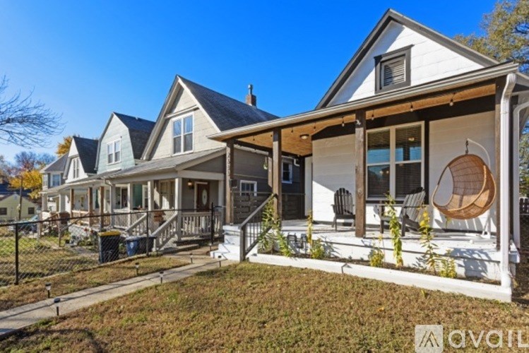 A white house with a porch and a hanging chair.