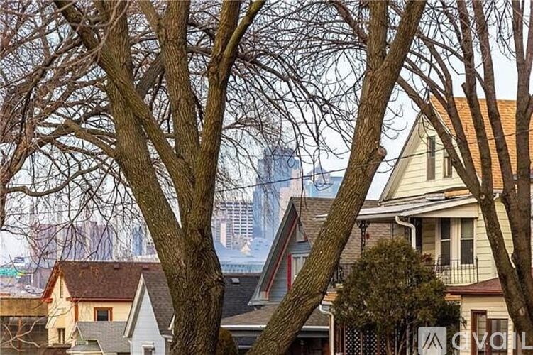 A view of a residential area with houses and trees in the foreground and a city skyline in the background.