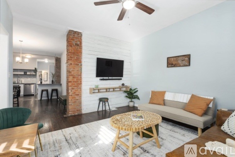 A living room with a brick column and a flat screen TV mounted on the wall.