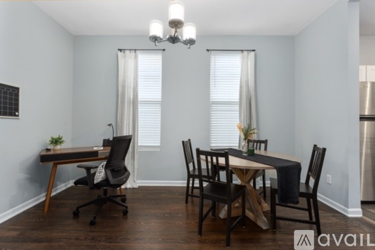 A dining room with a table set for two and a chandelier hanging from the ceiling.