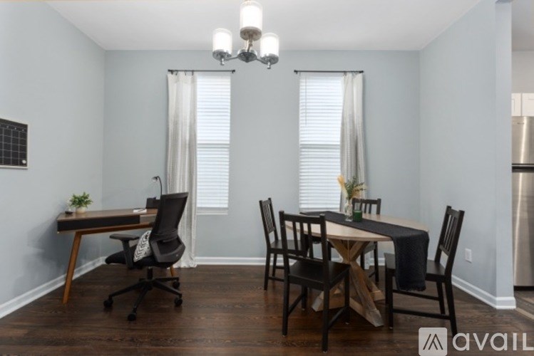A dining room with a table set for two and a chandelier hanging from the ceiling.