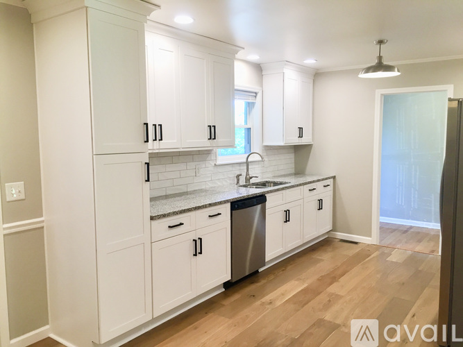A kitchen with white cabinets and a wooden floor.