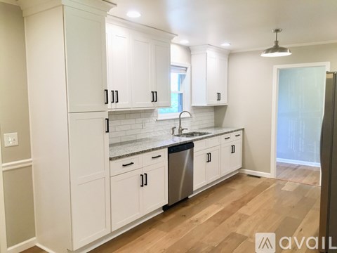 A kitchen with white cabinets and a wooden floor.