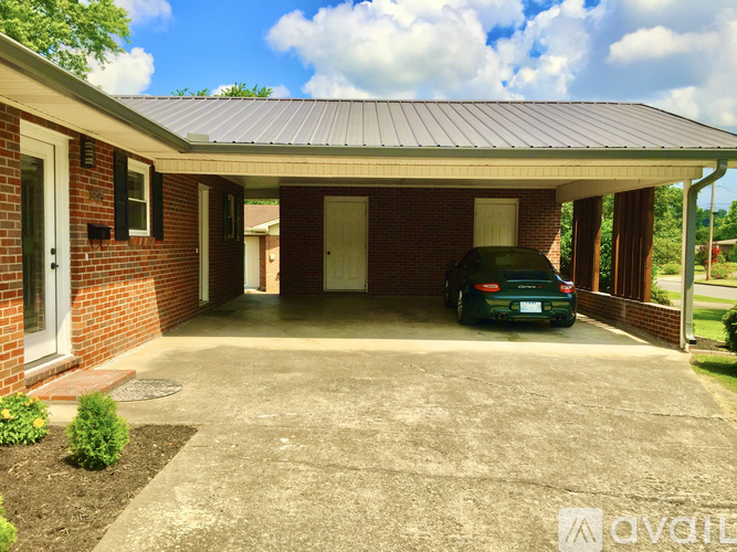 A car is parked in a driveway under a covered garage.