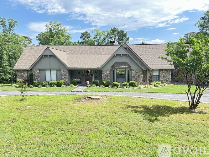 A house with a brown roof and a white door is surrounded by greenery.