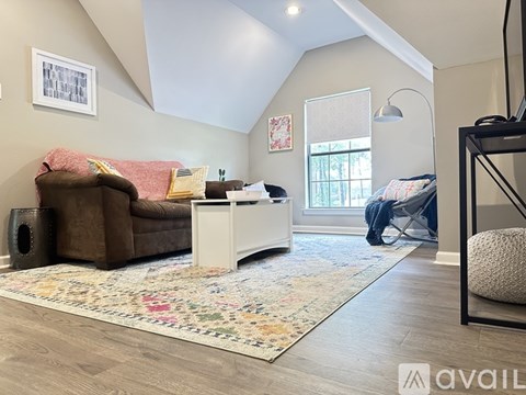 A living room with a brown couch, a white coffee table, and a rug with a floral pattern.