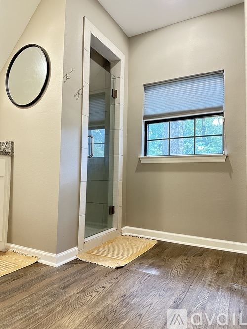 A room with a wooden floor and a window with blinds.