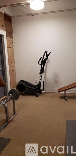 A room with a vacuum cleaner and a wall-mounted exercise bike.
