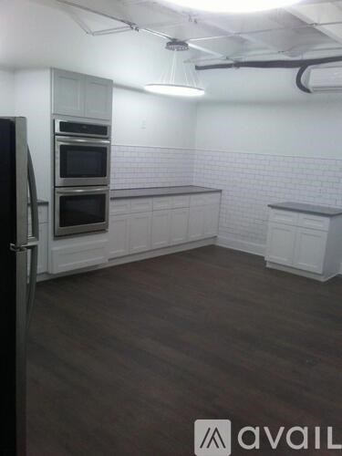 A kitchen with white cabinets and a black fridge.