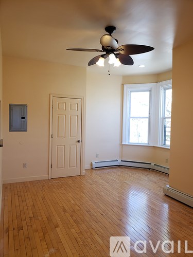 A room with a ceiling fan and wooden floors.