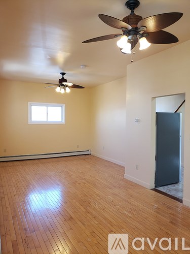 A room with a ceiling fan and wooden flooring.