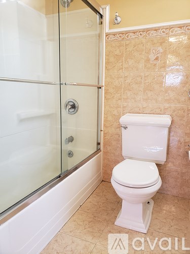 A white toilet in a tiled bathroom with a glass shower door.