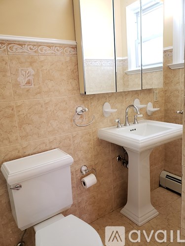 A bathroom with a toilet, sink, and mirror.