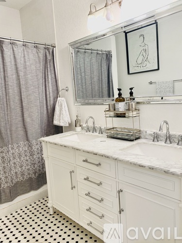 A bathroom with a white vanity and a shower with a grey curtain.