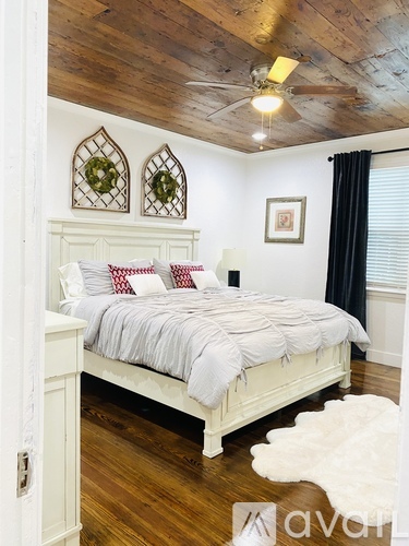 A bedroom with a white bed and wooden ceiling.