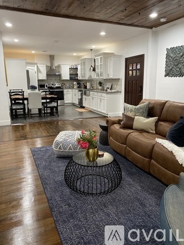 A living room with a brown couch and a grey rug.