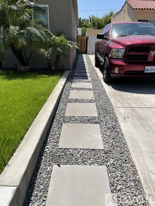 A red truck is parked on a driveway with a gravel path.