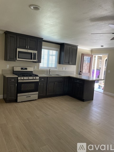 A kitchen with black cabinets and a white stove top oven.