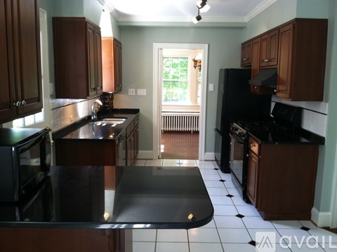 A kitchen with black appliances and brown cabinets.