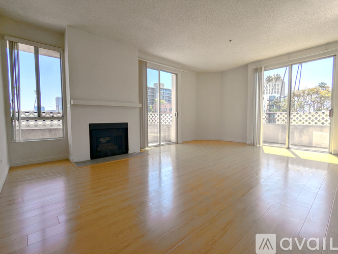A spacious room with wooden flooring and a large window.