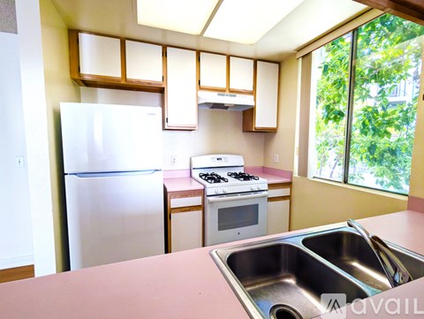 A kitchen with a stove, sink, and refrigerator.
