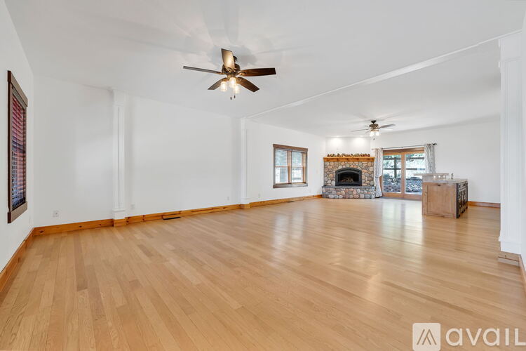 A spacious room with wooden floors and a fireplace.