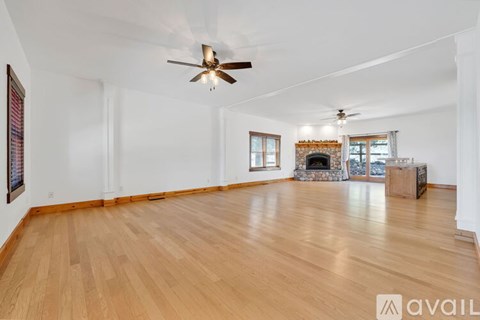 A spacious room with wooden floors and a fireplace.