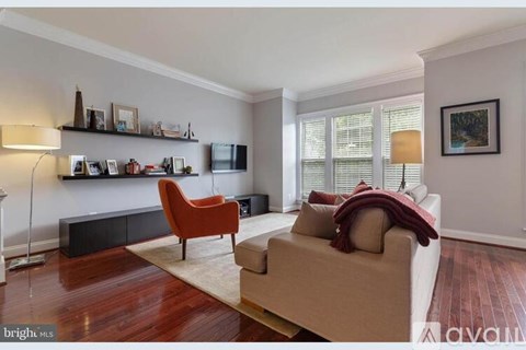 A living room with a brown couch, a red chair, and a television on the wall.