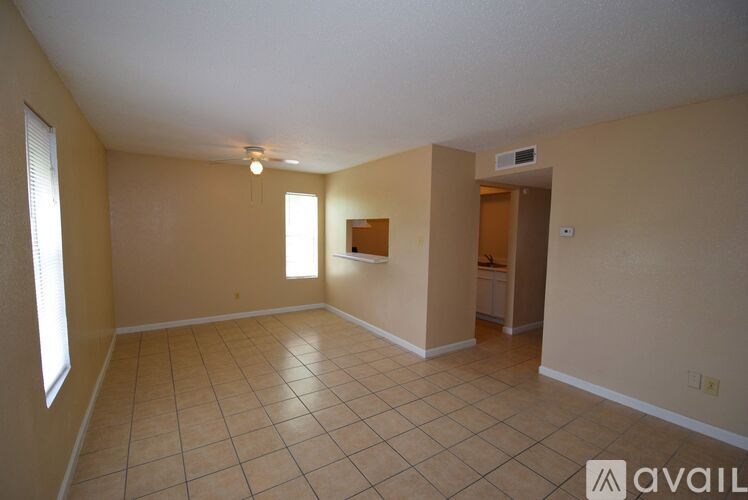 A spacious room with tile flooring and a window on the left side.