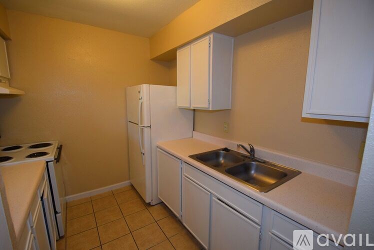 A kitchen with a stove, sink, and cabinets.