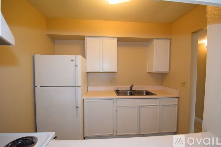 A kitchen with a white refrigerator, sink, and cabinets.
