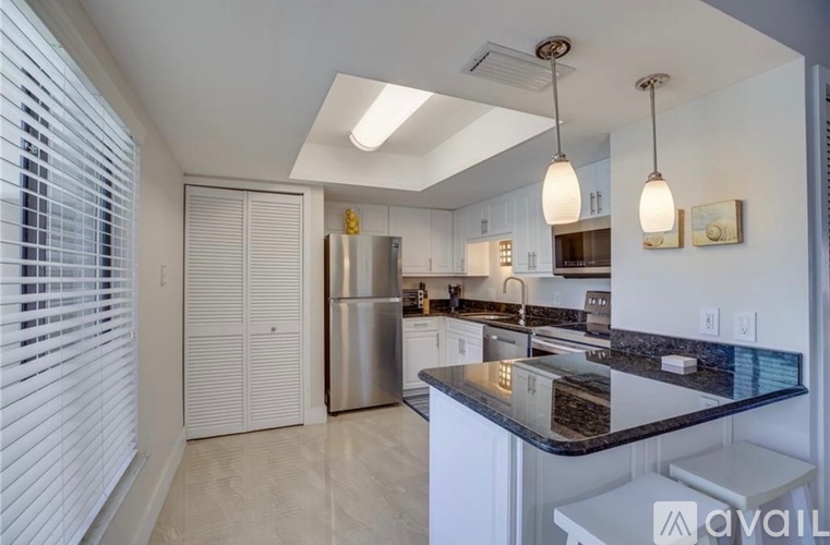 A kitchen with a black countertop and stainless steel appliances.