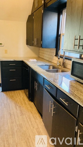 A kitchen with black cabinets and a granite countertop.