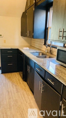 A kitchen with black cabinets and a granite countertop.