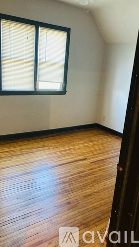 A room with wooden flooring and a window with blinds.