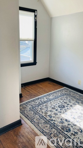 A room with a rug on the floor and a window with blinds.