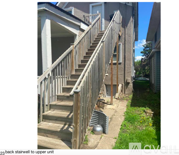 A wooden staircase leads up to a house's upper unit.