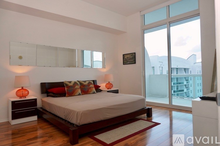 A bedroom with a large bed, two lamps, and a painting on the wall.