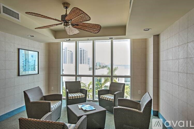 A living room with a fan, chairs, and a table with a book on it.