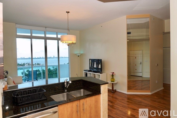 A kitchen with a sink, stove, and a window overlooking the beach.