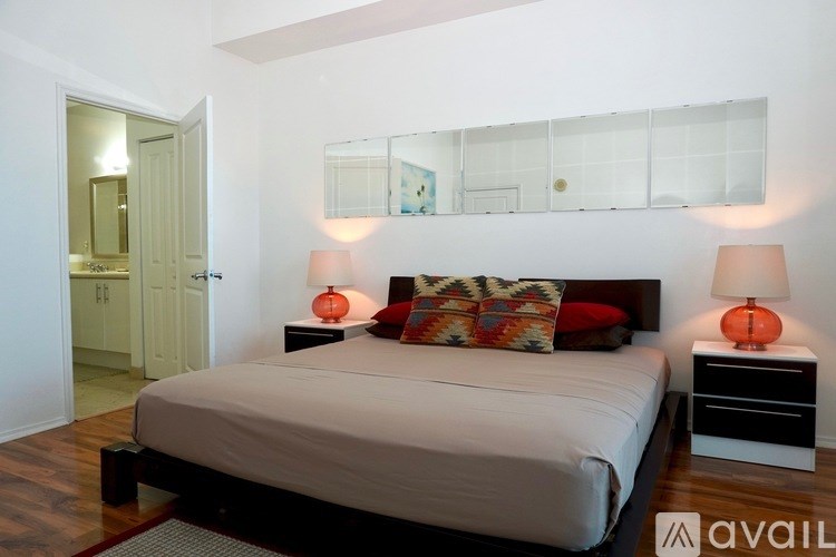 A bedroom with a bed, two lamps, and a dresser.