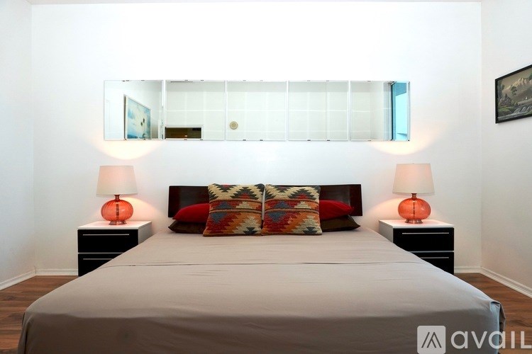 A bedroom with a large bed, two lamps, and a painting on the wall.