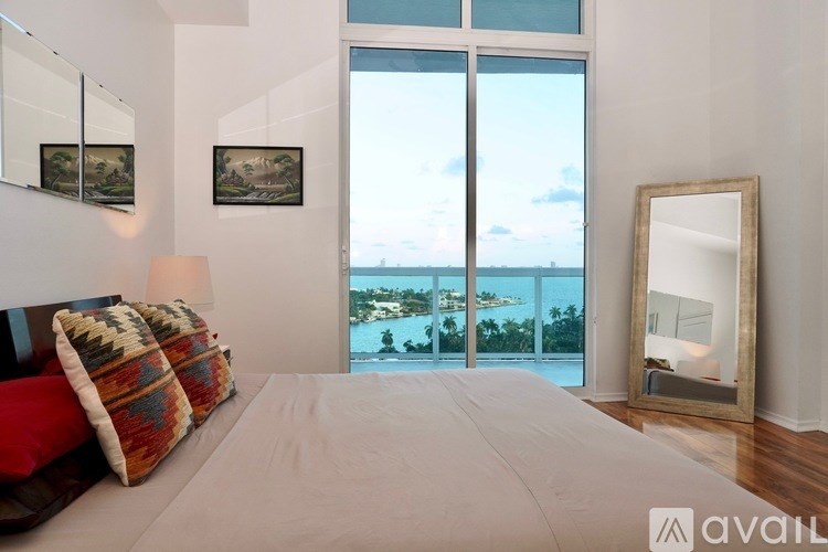 A bedroom with a large bed and a view of the ocean through the sliding glass doors.