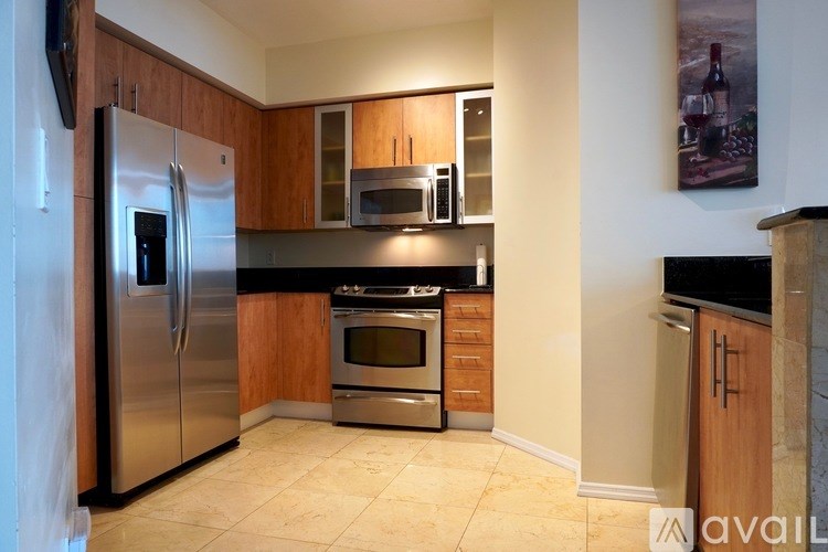 A kitchen with a stainless steel refrigerator and wooden cabinets.